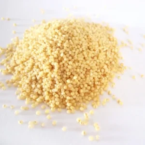 Millet grain: small round pale yellow seeds heaped on a white background