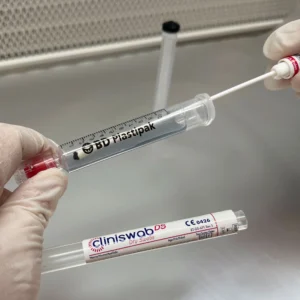 Attaching a swab to a syringe under a laminar flow hood, gloved hands working