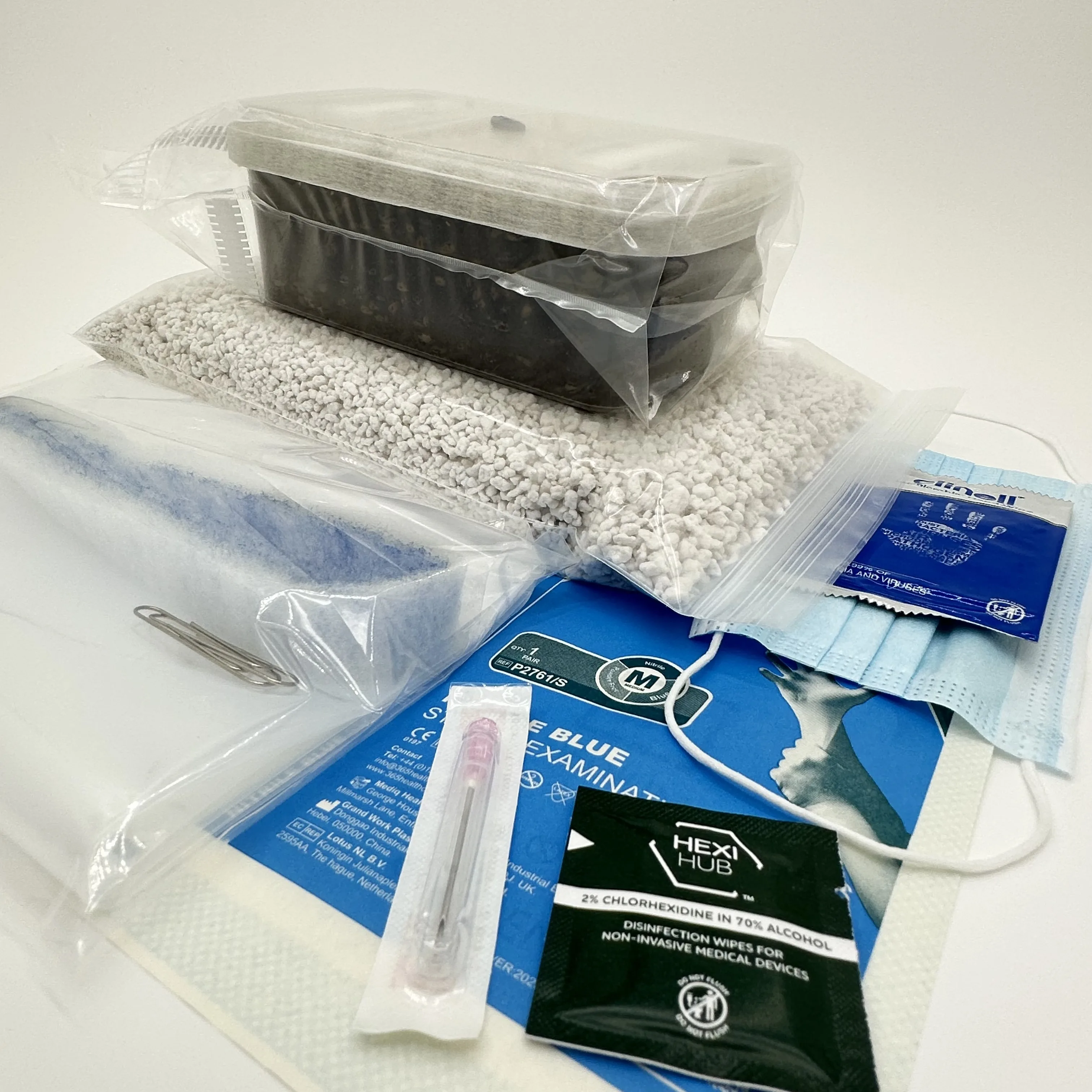 The Grow Kit version of the XL Cylocybe Special MykoBox seen from the side, its sealed tub of dark substrate resting on the bag of perlite, with the liner bag, nitrile gloves, face mask, alcohol and chlorhexidine wipes and a sterile syringe laid out in front