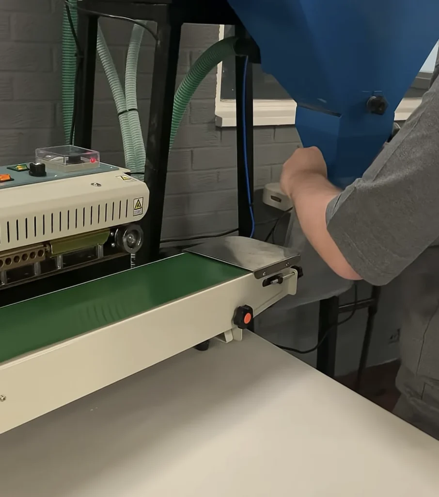 Filling bags from our blue hopper beside the band sealer and its green conveyor