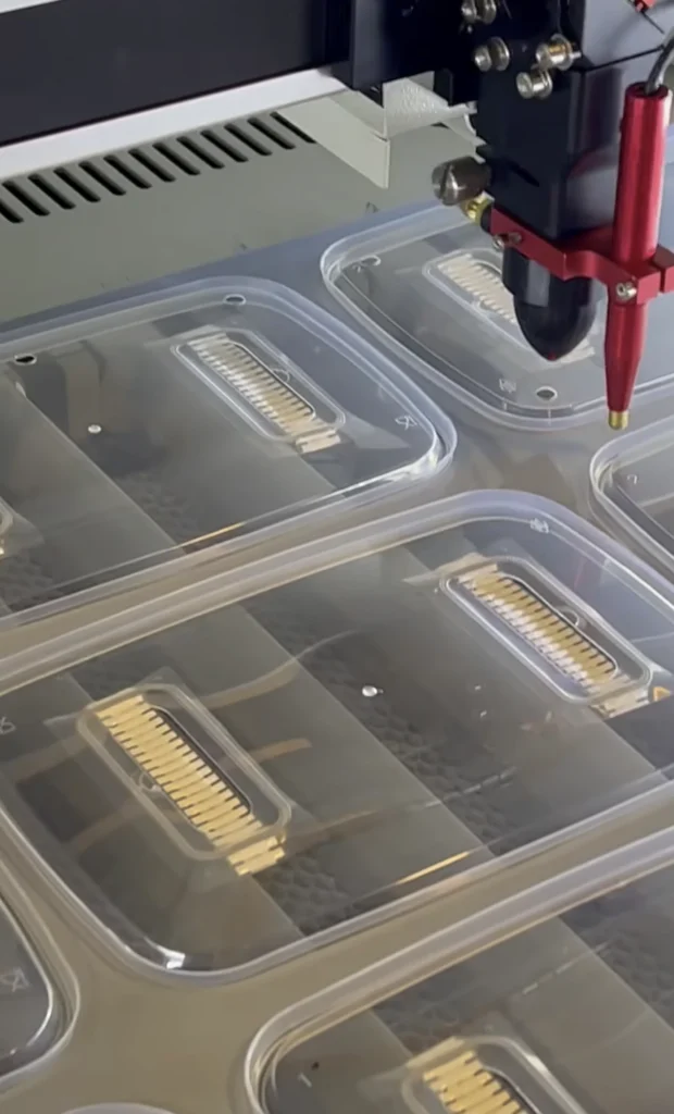 Close-up of our laser cutter head over clear grow box lids with filter strips