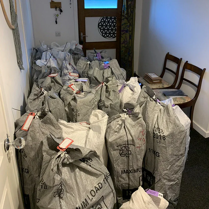 Royal Mail sacks of parcels packed and tagged, lined up in a hallway waiting for collection